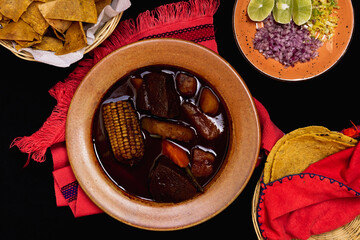Top view of mole de olla with tortillas and tortilla chips, Mexican food.