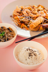 Bowl with rice and sesame seeds, Asian food dish on pink background.