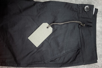 Top view of black pants fashion folded and empty paper label. Close u