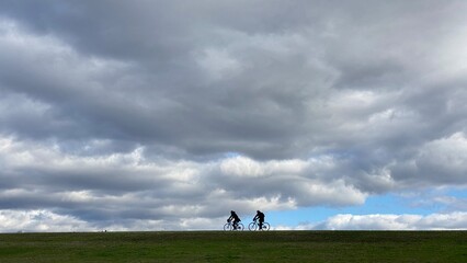 秋の河川の堤防でサイクリングしている人の姿