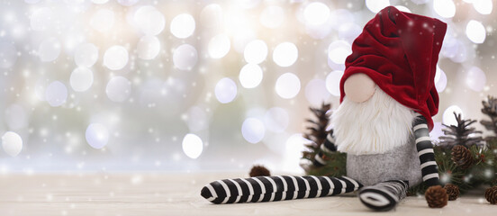 Christmas gnome on light background with glowing lights. Banner for design