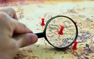 Magnifying glass looking at pin in a map