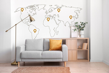 Interior of light living room with grey sofa and printed world map on wall