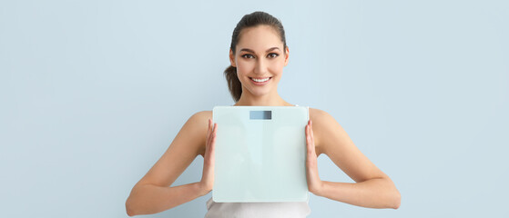 Young woman with scales on light background. Weight loss concept - obrazy, fototapety, plakaty