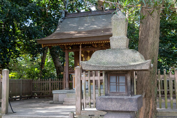 小さな神社の前に立つ古い石灯籠