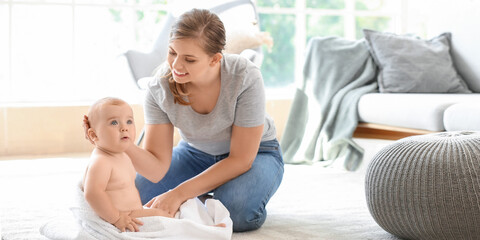 Mother wiping her cute little baby after bathing at home