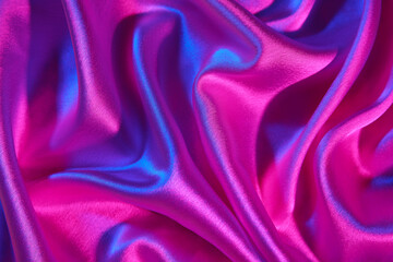 Crumpled silky fabric in neon light as background