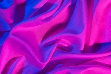 Crumpled silky fabric in purple neon light as background