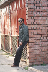 man wearing black glasses standing with wall
