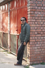 MAN wearing black glasses stadnignw ith wall