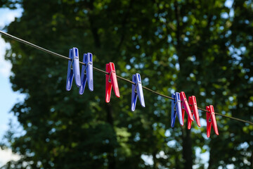 Many colorful clothespins hanging on rope outdoors