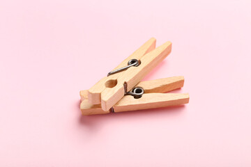 Two wooden clothespins on pink background