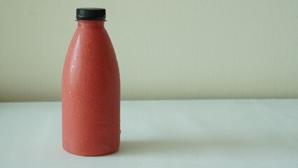 A plastic bottle contains cool red guava juice