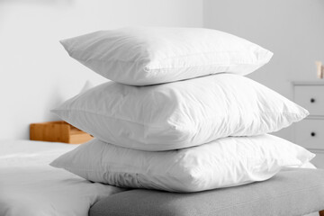Fototapeta na wymiar Stack of white pillows on bed in light room