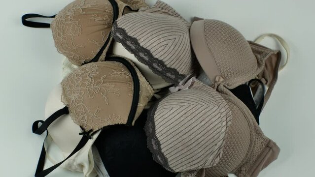 Close-up of a female bras piled up in a heap on a light background. Colorful erotic women's bras. Women's underwear. The concept of women's wardrobe. Flat lay