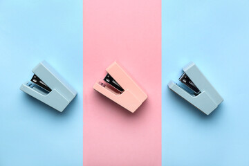 Office staplers on color background