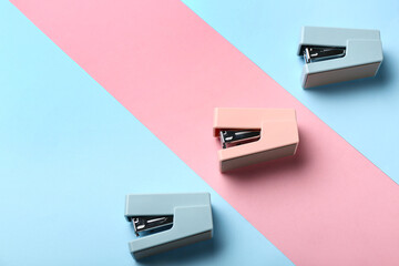 Office staplers on color background