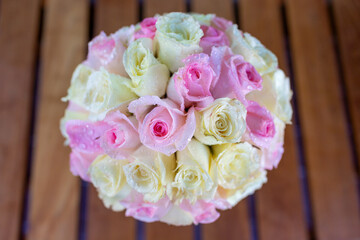 A large bouquet of roses in a glass on the table there are water droplets on the petals Look fresh and beautiful with pink and yellow flowers.