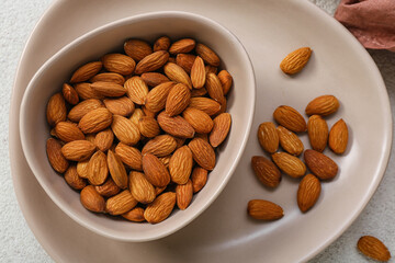 Plate with bowl of almonds on white background