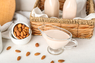 Gravy boat of almond milk and nuts on light background