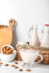 Gravy boat of almond milk and nuts on light background