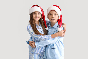Little children in pajamas hugging near light wall
