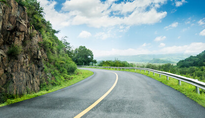 Winding road with steep rocky cliff in the mountains