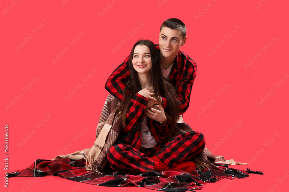 Sticker Young couple in checkered pajamas on red background