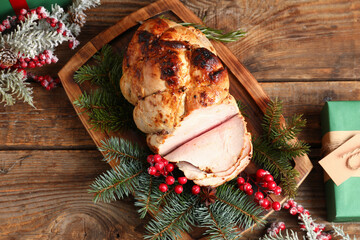 Board with tasty ham, Christmas branches, rowan and gifts on wooden background