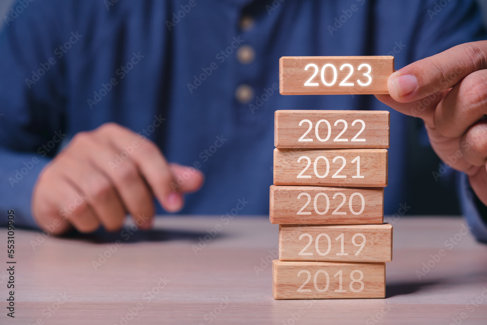 Aufkleber man hand build stack of wood cube building block with text 2023 on it