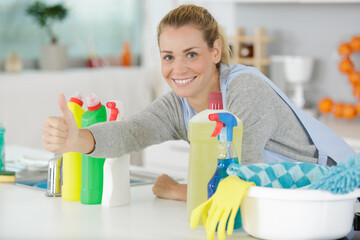 woman amongst cleaning products holding thumbs-up