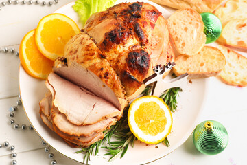 Plate with tasty ham, orange and Christmas decor on white wooden table, closeup