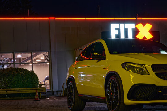 Dortmund, Germany 20220824 - yellow sports car Mercedes paked at park lot of  fitness centre fitx at night, glowing neon