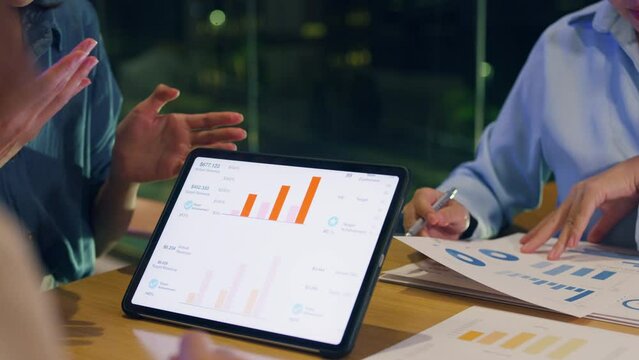 Close-up asia businesspeople meeting plan analysis statistics brainstorm and header of team hold tablet point graph chart and employee take note at home office night. Finance strategy success concept.