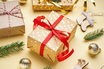 Gift boxes with Christmas toys and fir branches on beige background, closeup