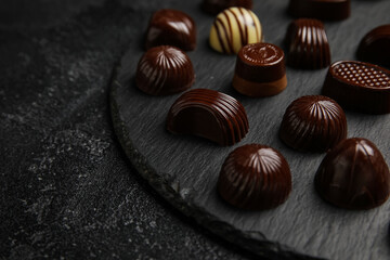 Board with chocolate candies on dark background, closeup