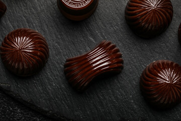 Chocolate candies on black wooden board, closeup