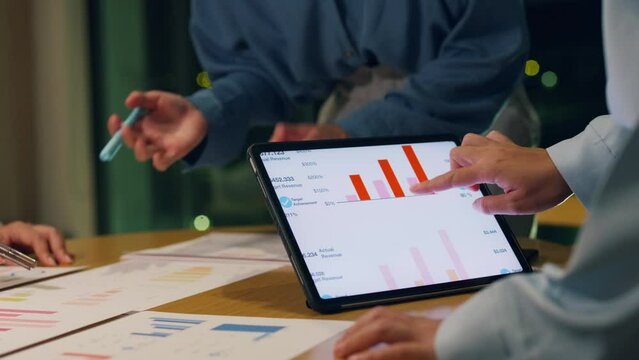 Close-up asia businesspeople meeting plan analysis statistics brainstorm and header of team hold tablet point graph chart and employee take note at home office night. Finance strategy success concept.