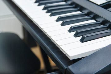 Close side view of shiny black and white piano keys. Focus on the fourth black key from the center...
