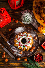 Composition with tasty Christmas cake, hazelnuts, cranberry and decorations on wooden background