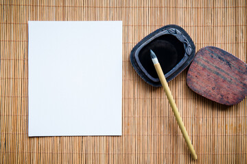 Abstract white paper with bamboo calligraphy brush and inkstone on old wooden table. picture for...