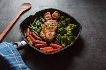 Chicken steak and vegetables saute in a pan. Close up, selective focus.