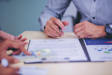 Businessman signing loan agreement for cash money from banker. Selected focus