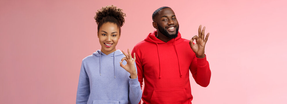 Two African-american Skilful Coworkers Professionals Assured Friend Everything Perfect Smiling Broadly Delighted Nodding Agree Approval Gesture Show Okay Ok Not Bad Choice Sign, Pink Background