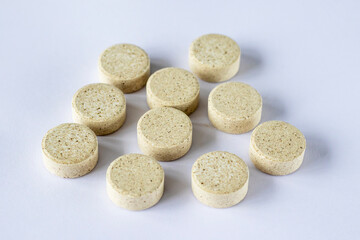 Round puck tablets of irregular beige color on a white background. Supplements DGL liquorice root. sustainability 