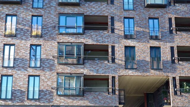 Apartment building with stone cladding used as decorative facade. Balconies and windows of multi-story housing project in residential district, marble or granite veneer applied to the exterior wall.