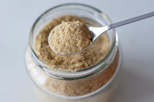Nutritional yeast inactive in a small spoonful close-up. Healthy vegan, vegetarian, superfood concept with high vitamin B1 content, sustainability 