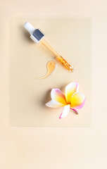 Top view of Pipette with liquid serumand frangipani flower on light beige background .Flat lay still life composition