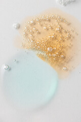 Different cosmetic swatch on white background. Light blue and gold smears texture, gel, serum oil,...