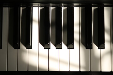 Naklejka premium Sunlight on Piano, keyboard close up instrument playing music, practing and celebrate. Top view of keys